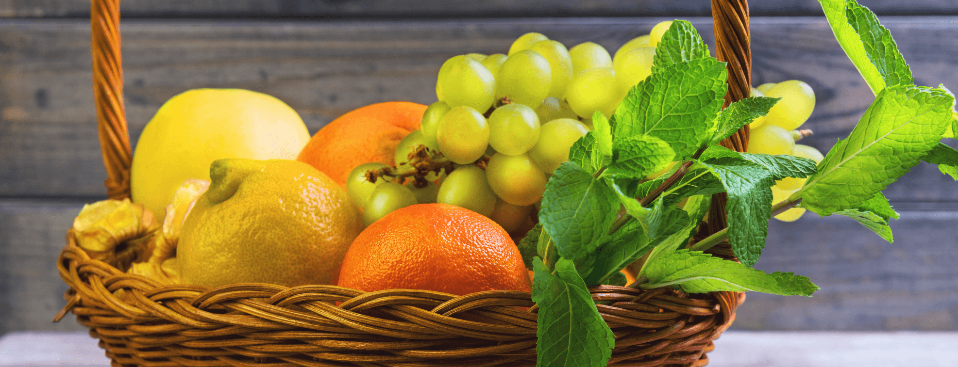 Apples, tangerines, grapes, lemons and other round fruits in a basket